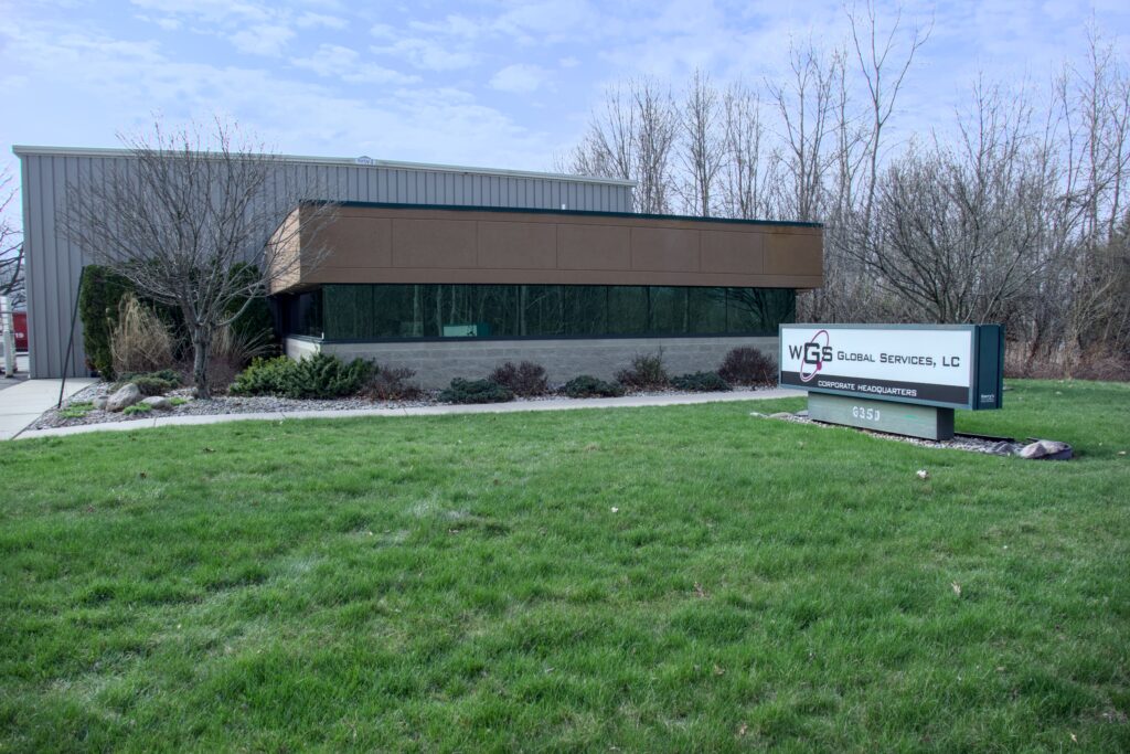 WGS Global Services corporate headquarters building in Grand Blanc, Michigan, featuring a modern design, landscaped front yard, and prominent signage.