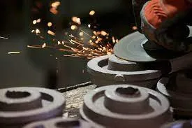 Worker grinding metal parts with sparks flying, showcasing precision in part finishing for improved manufacturing quality.