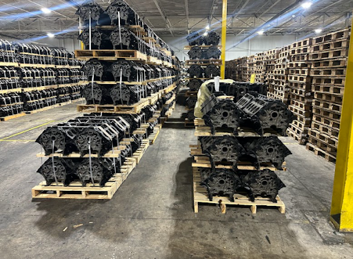 Warehouse interior showcasing stacked metal components on pallets, emphasizing sustainable manufacturing practices at WGS Global Services.