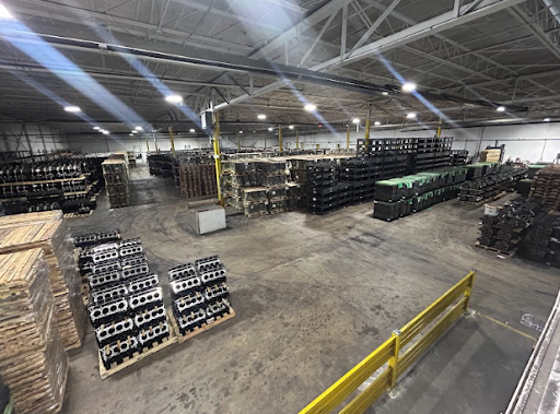 Warehouse interior with stacks of metal components and pallets, illustrating quality control in metal finishing for manufacturing.